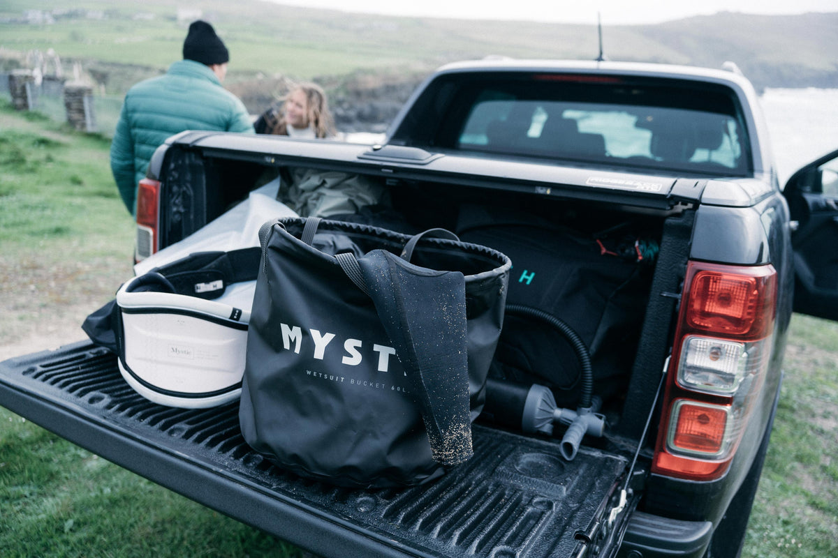 Mystic Happy Hour Wetsuit Changing Bucket in de laadbak van een pick-up bij de kust