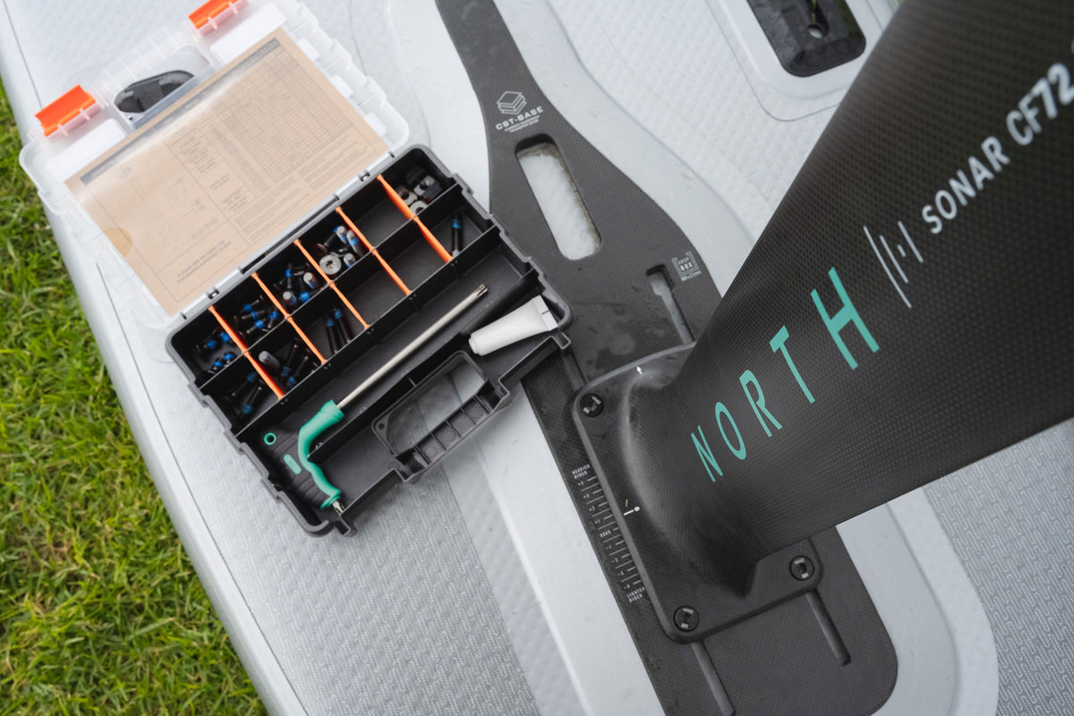 North Sonar Session Saver Box open op een foilboard op het gras, naast een Sonar CF72 foilmast