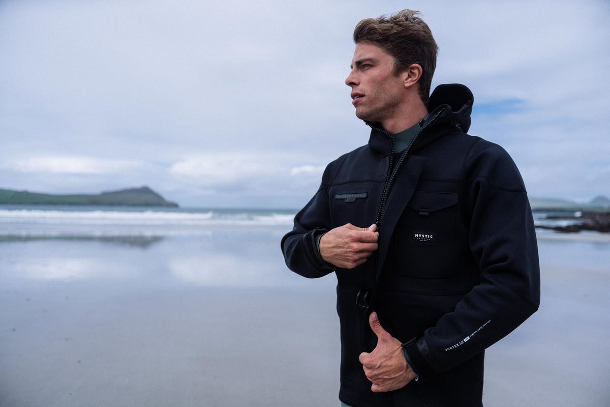 Man in een Mystic Vortex Fidlock Neoprene Jacket op het strand