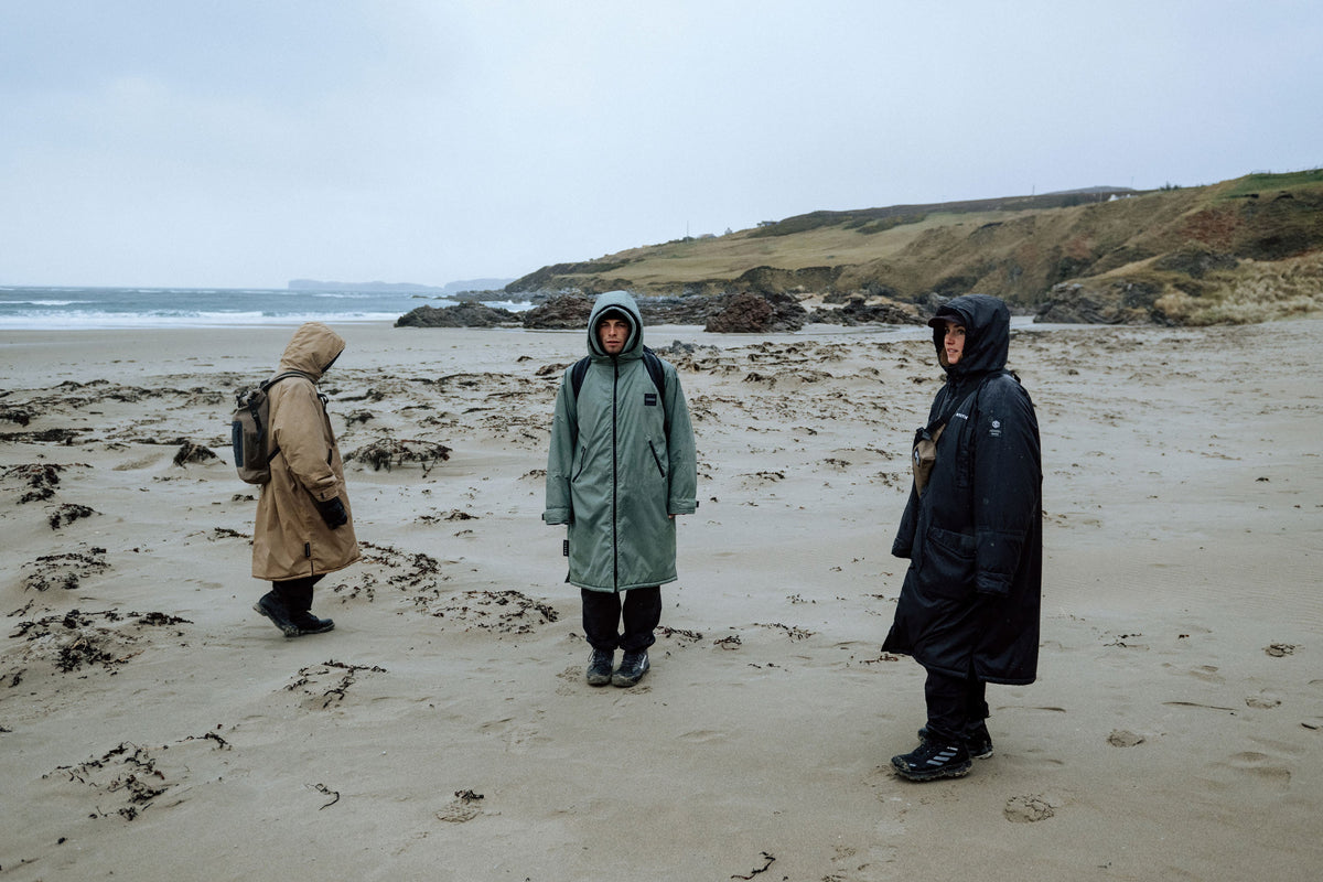 Drie Mystic Poncho Explore-jassen op het strand