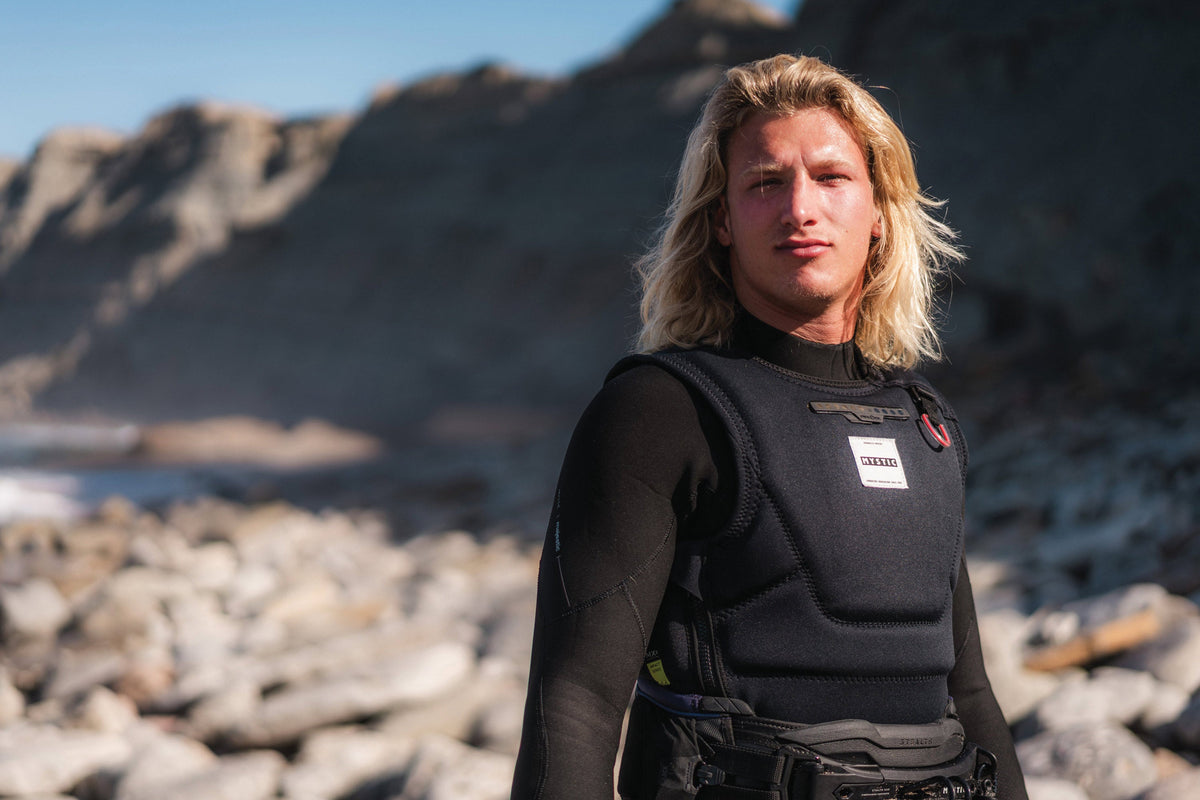 Kiter met de Mystic Solace Impact Vest en trapeze op het strand