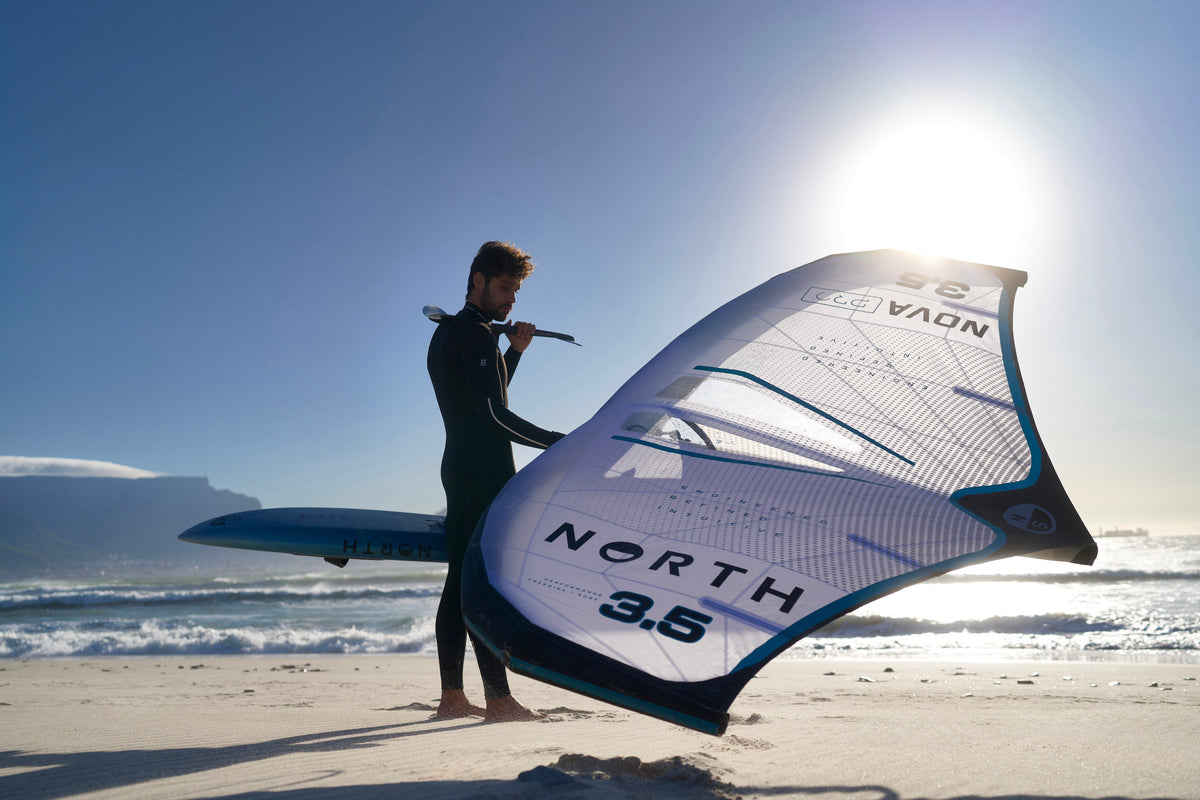 Wingfoiler met de North Nova Pro Wing 2025 in 3.5 op het strand, met een foilboard onder de arm en de zon in de rug