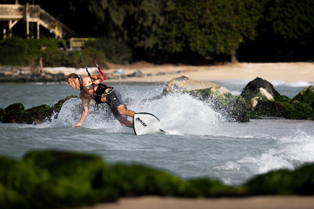 Kitesurfen op de Naish Kokomo 2025 in ondiep water langs de rotsen op Maui