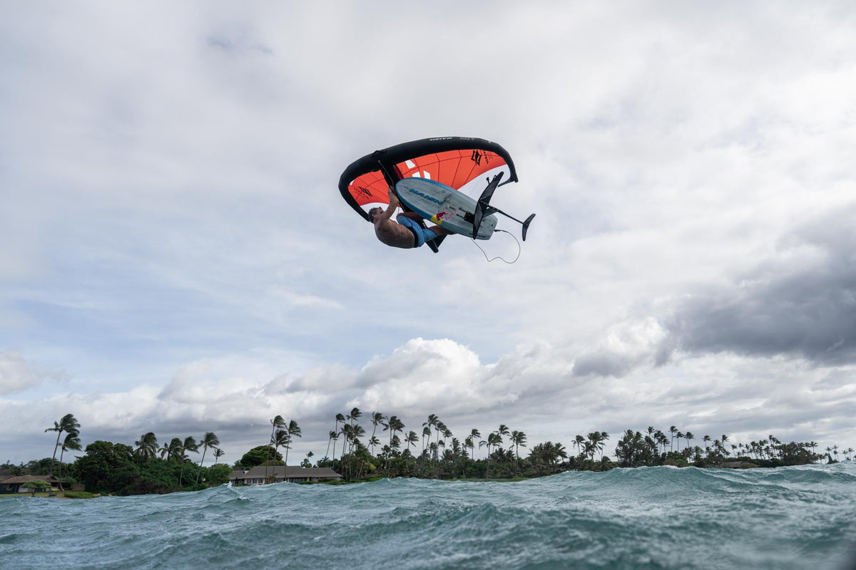 Naish ADX wingfoil wing hoog in de lucht boven de kust