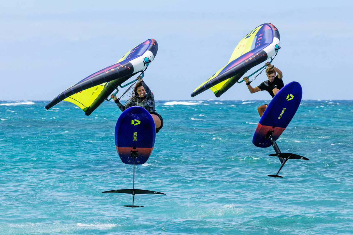 Twee wingfoilers boven het water met de Duotone Glide 2.0 SLS front wing zichtbaar onder hun boards