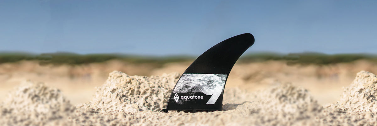 Aquatone 9 inch center fin rechtop in het zand op het strand