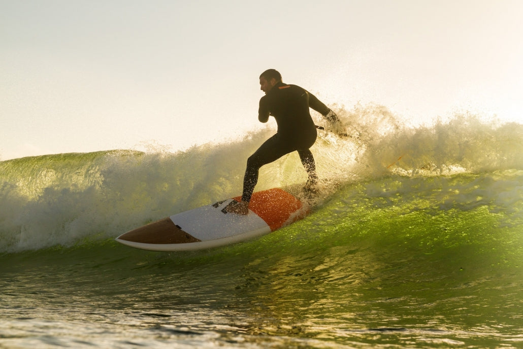 SUP-surfer maakt een bocht op een RRD Cosmo in een golf bij laag zonlicht