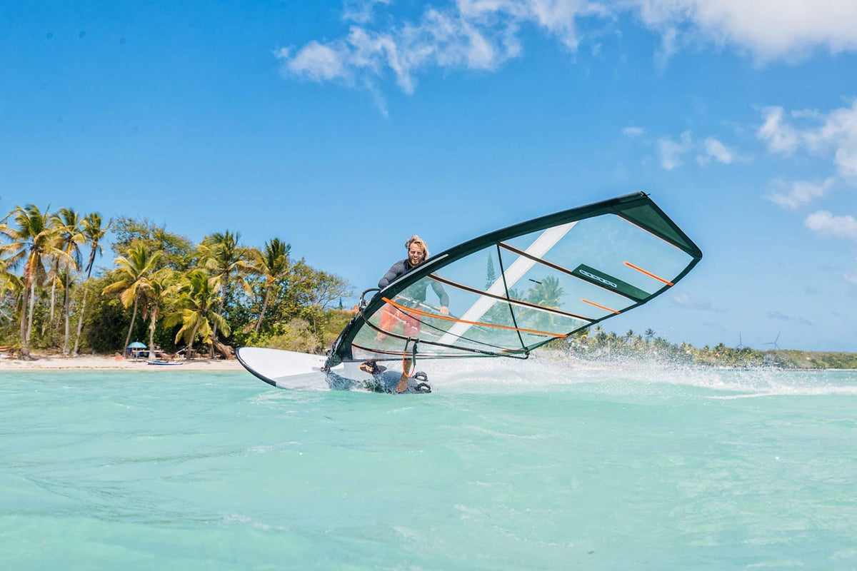 Windsurfer gijpt op de RRD Firemove LTD Y27 voor een palmenstrand met turquoise water