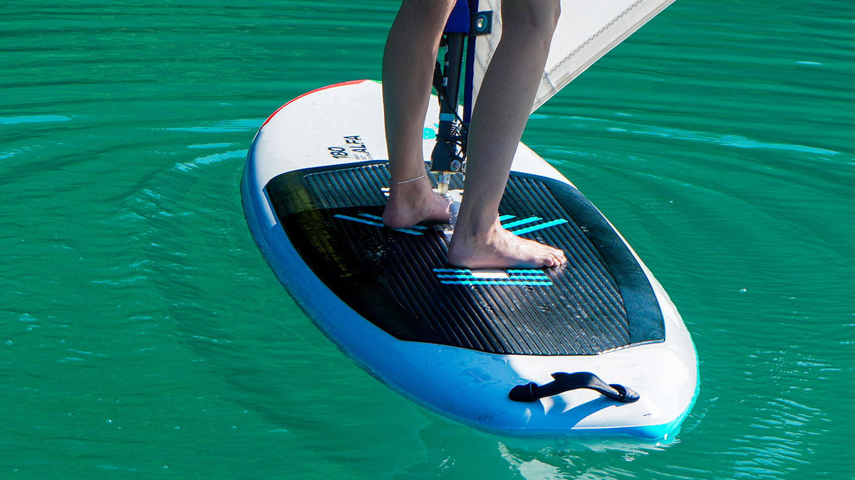 Duotone Alfa HD schoolboard tijdens het windsurfen op vlak turquoise water