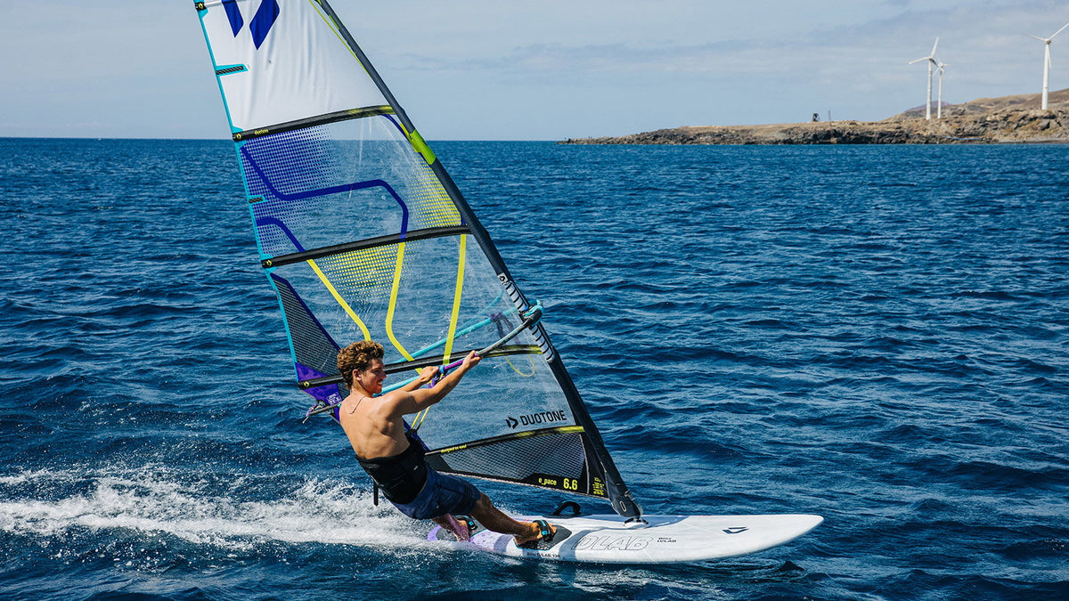 Windsurfer op de Duotone Blitz D/LAB op zee met rotsachtige kust op de achtergrond