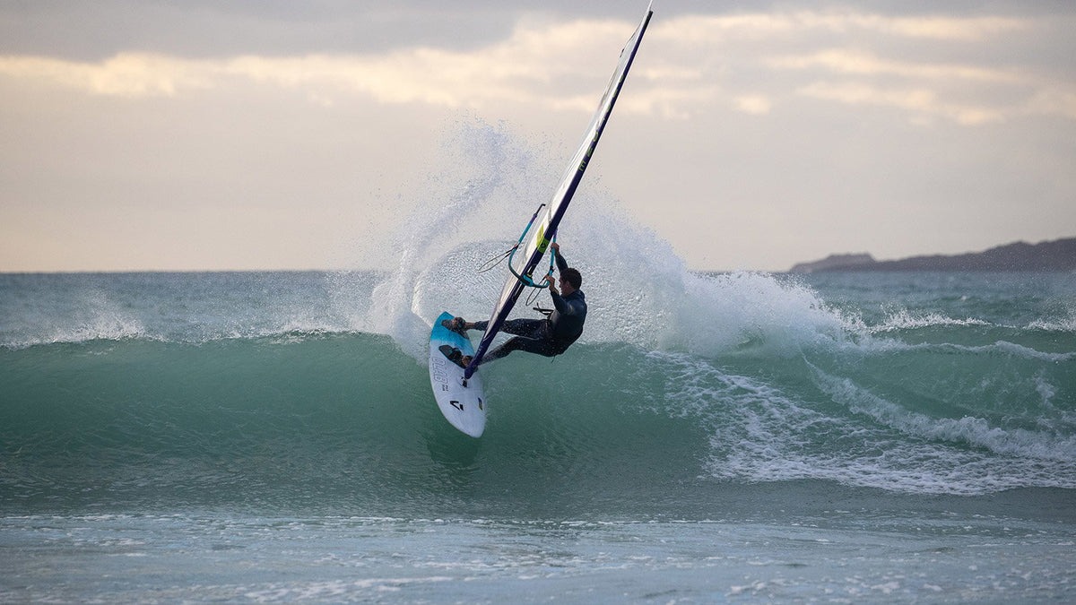 Duotone Grip (3) D/LAB windsurfboard in wit in een top turn op een golf