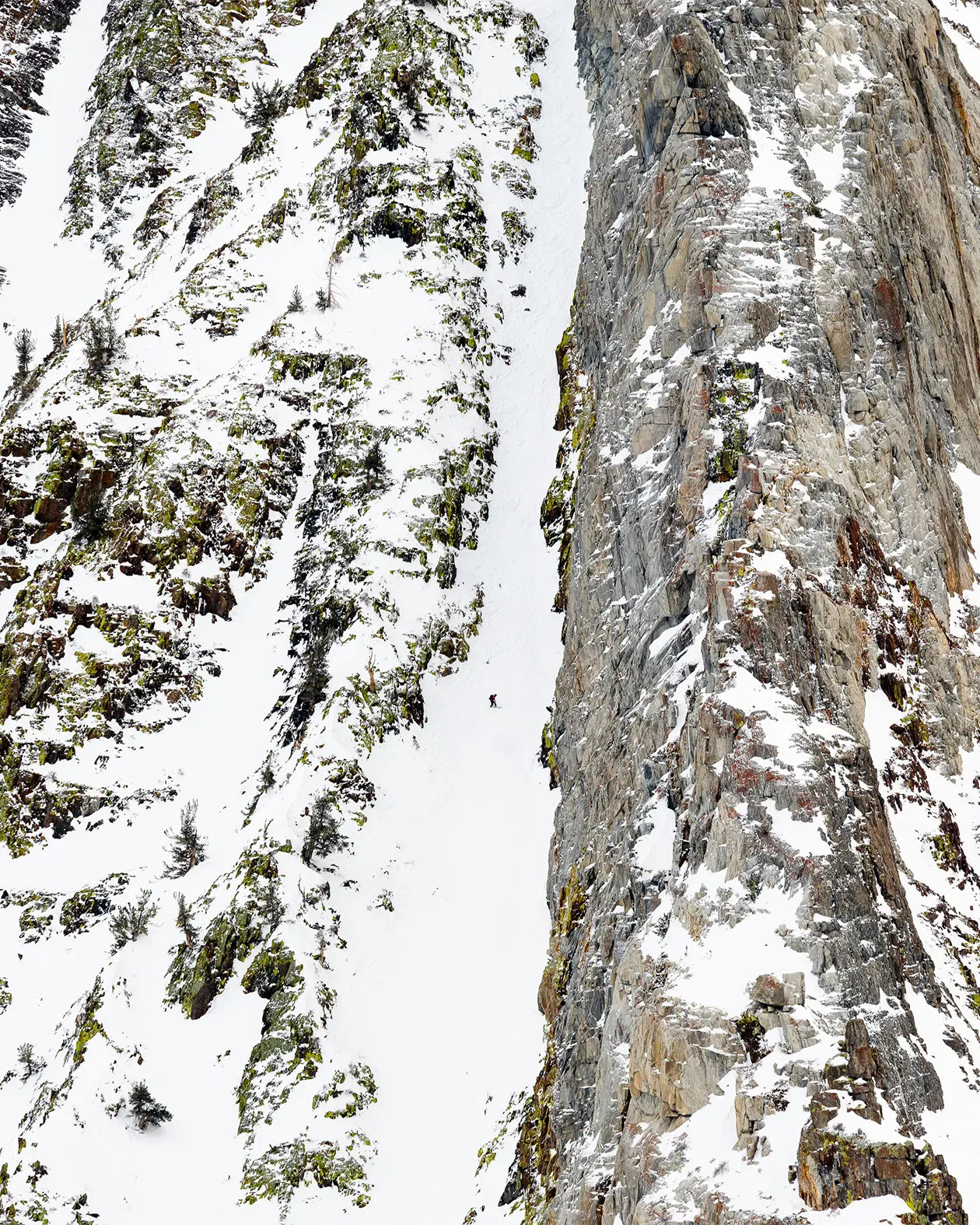 Jones Men's Ultralight Solution Splitboard, rider op een steile besneeuwde helling tussen rotsen