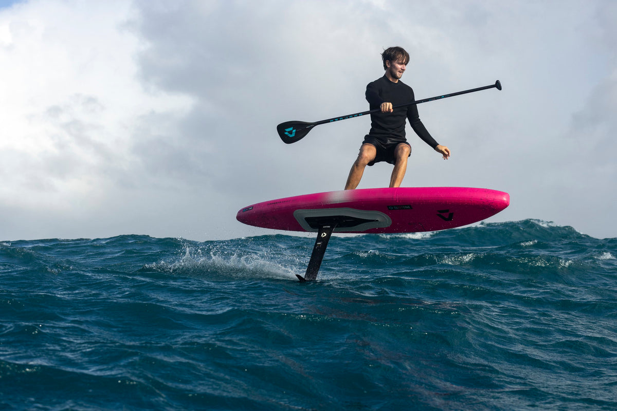 SUP-downwinder foilt met peddel op de roze Duotone Downwinder Air over open zee