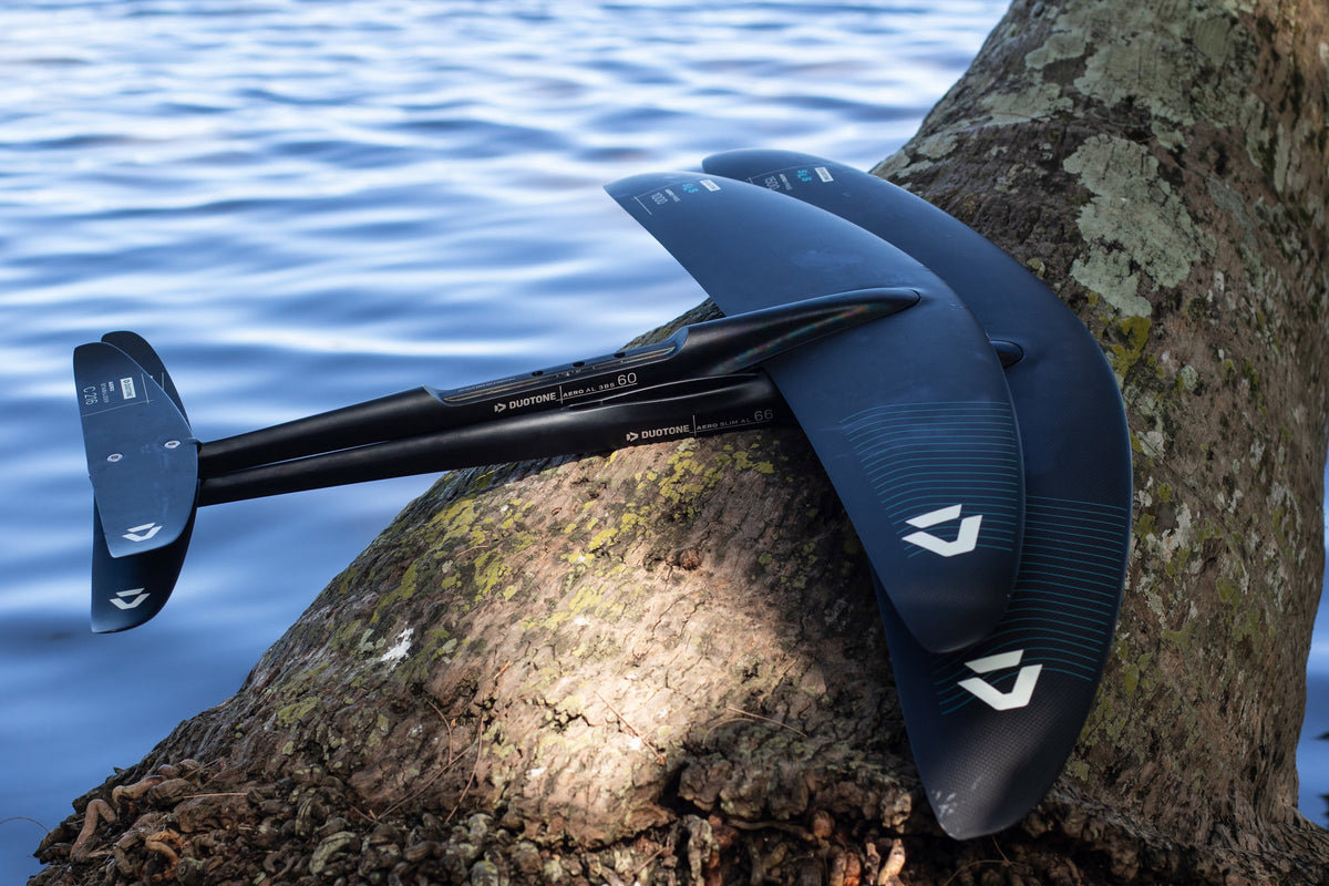Duotone Aero Free SLS front wings met mast en stabilizer op een boomstam aan het water