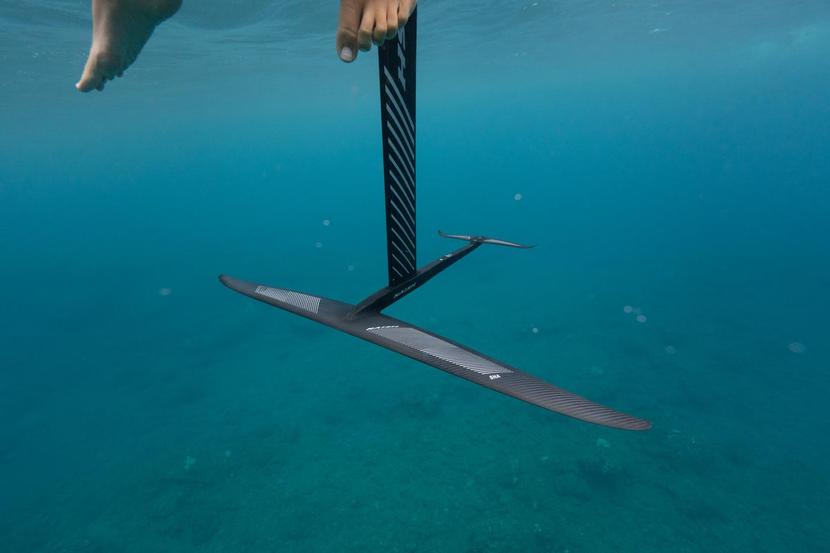 Naish SHA Semi Complete 2025 onder water: de lange carbon frontwing met SHA-opdruk en de stabilizer