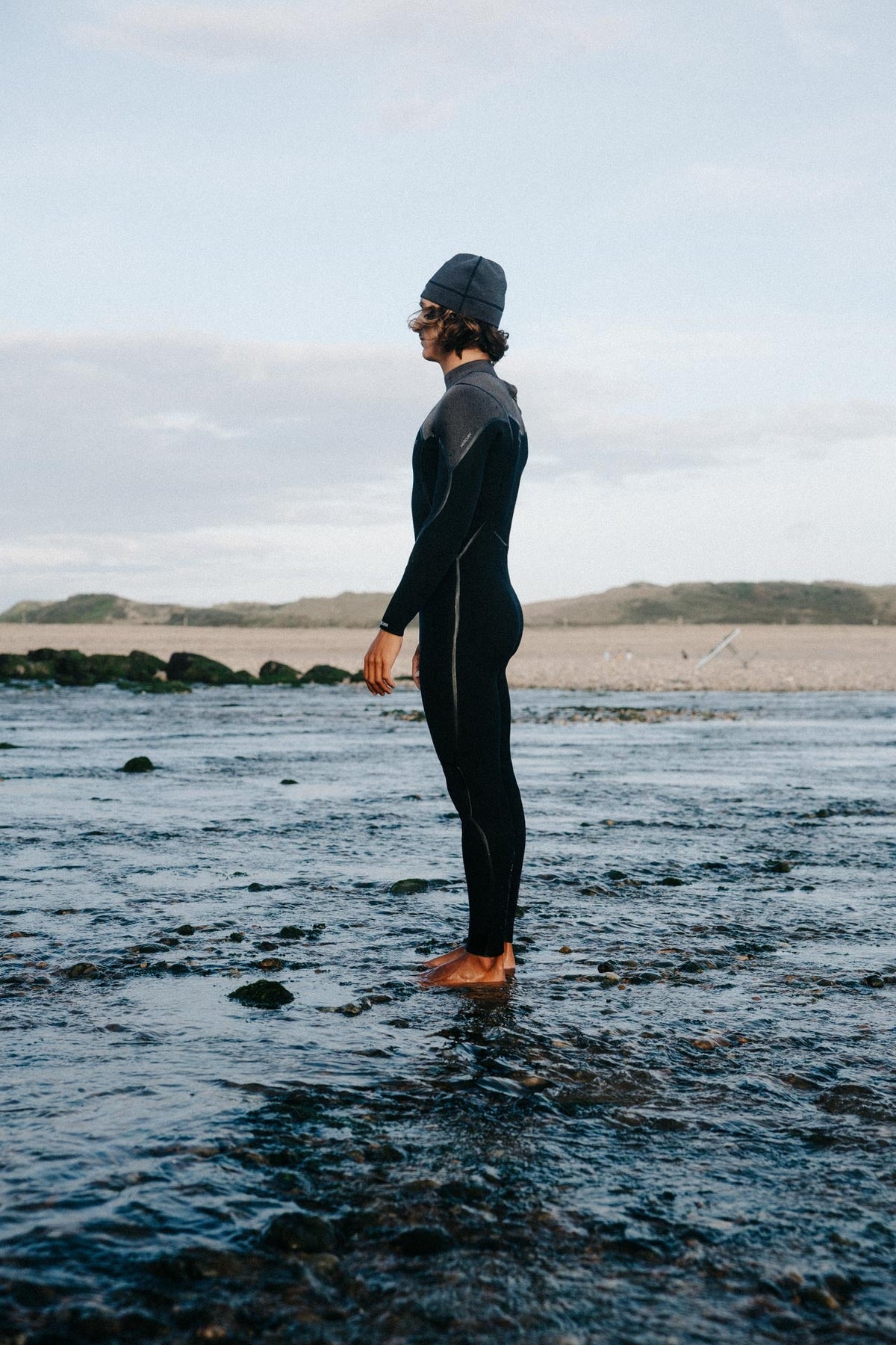 Rider in de Prolimit Mercury-wetsuit met neopreen muts aan de waterkant