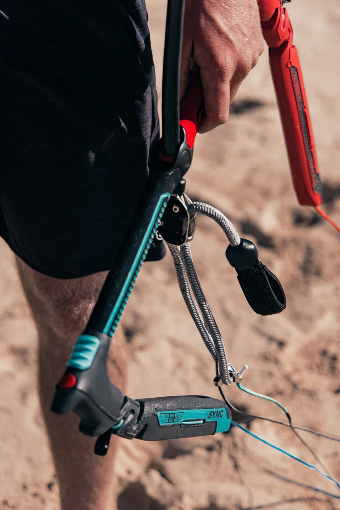 Naish Sync Bar in de hand op het strand, met chicken loop en trimlijn