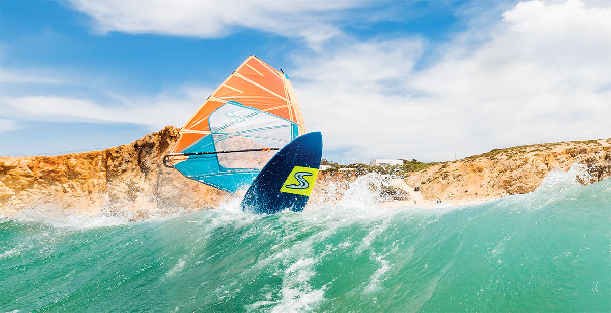 Wavesurfer met de Simmer Style Evoq 2024 in oranje op een golf