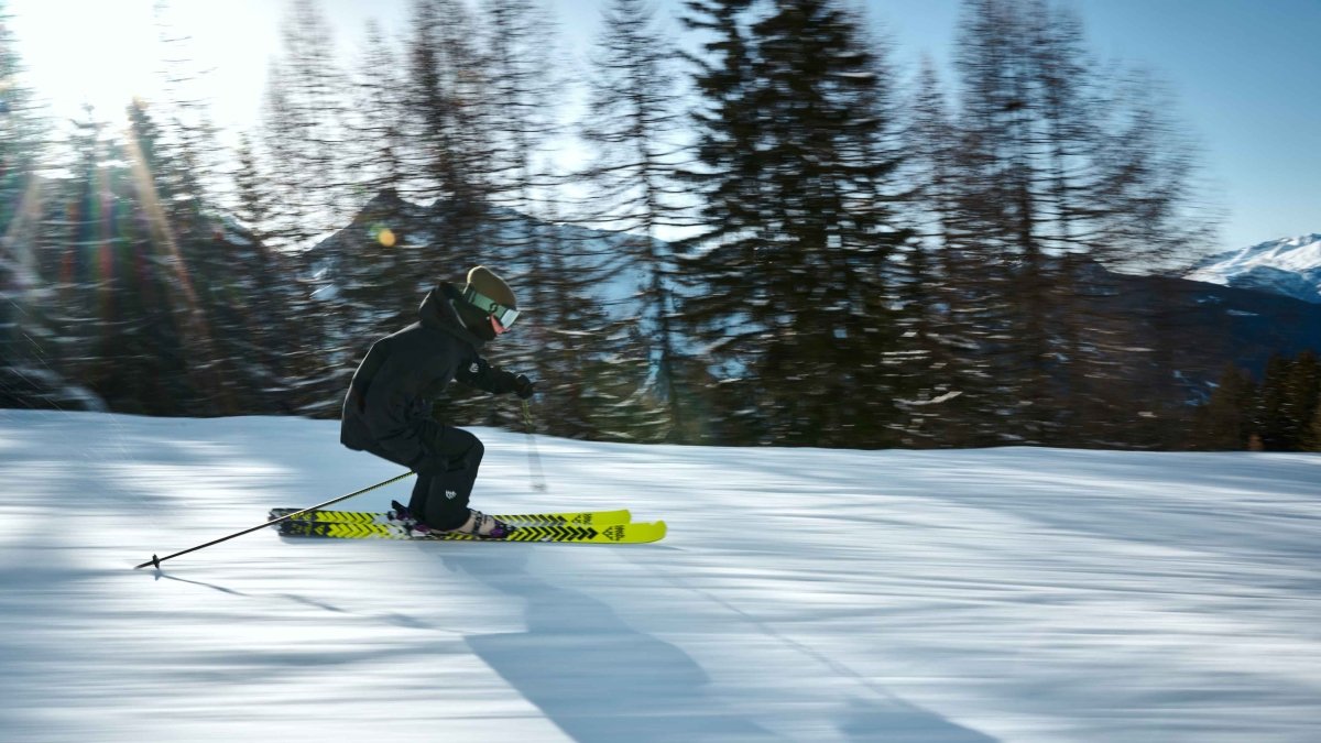 Black Crows Stans Poles zwart/geel, skiër maakt een bocht op de piste in de bergen