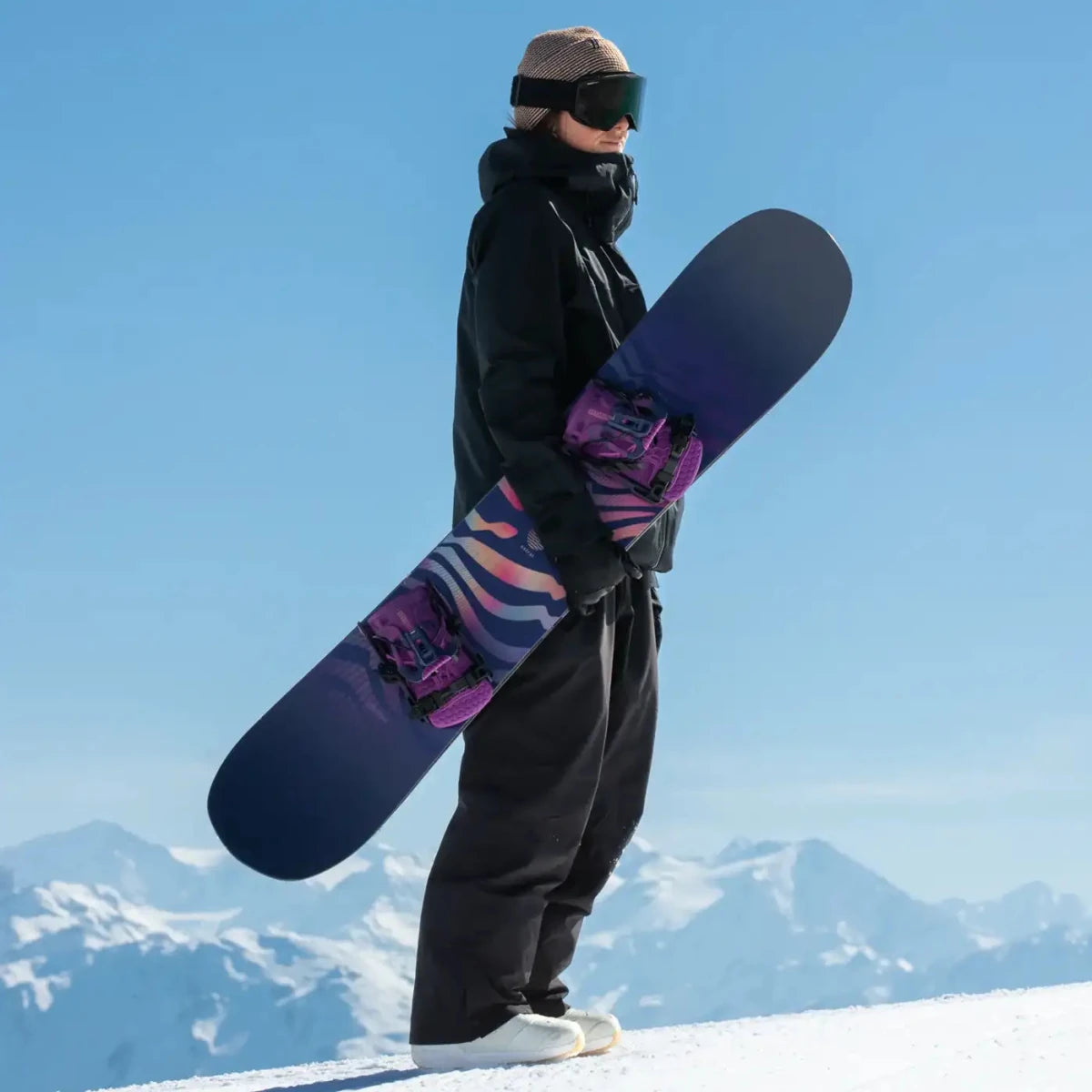 Flow Fenix Nightshade, rider met snowboard onder de arm in de bergen