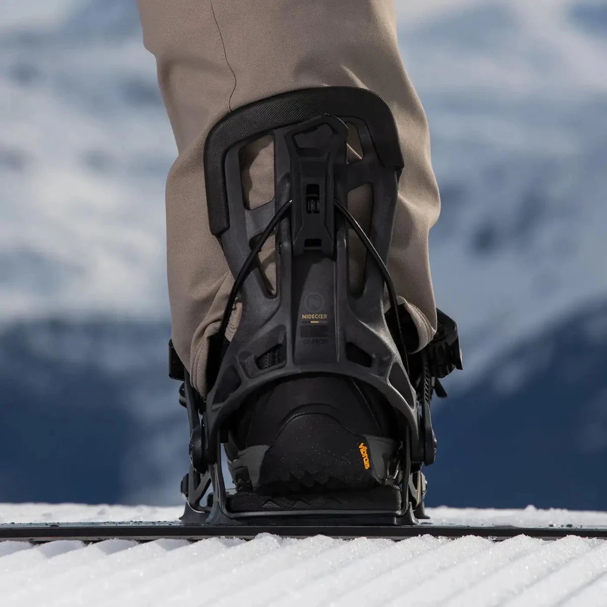 Flow NX2 Carbon Black, binding met boot op een snowboard in de sneeuw