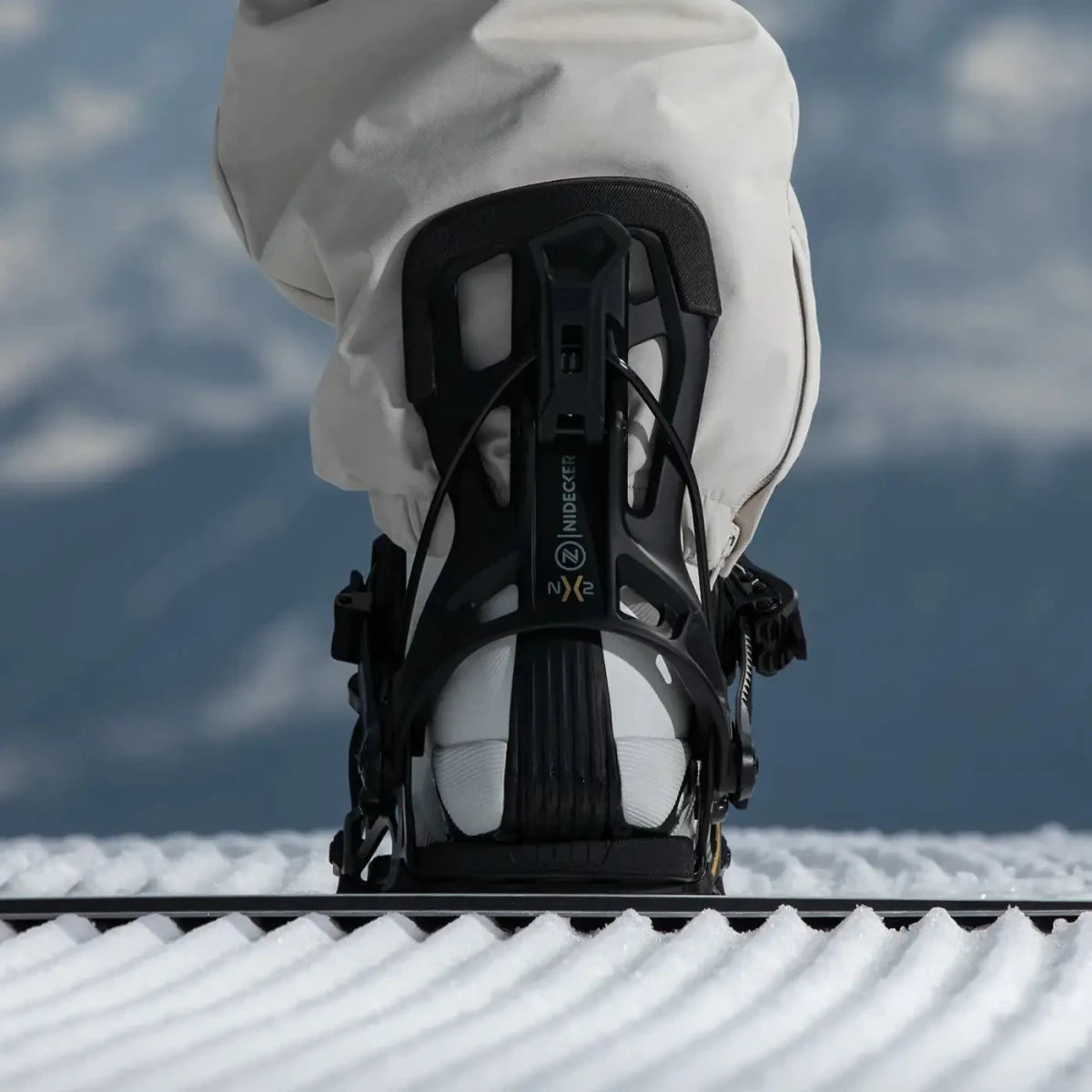 Flow NX2 Hybrid Black, binding met boot op een snowboard in de sneeuw