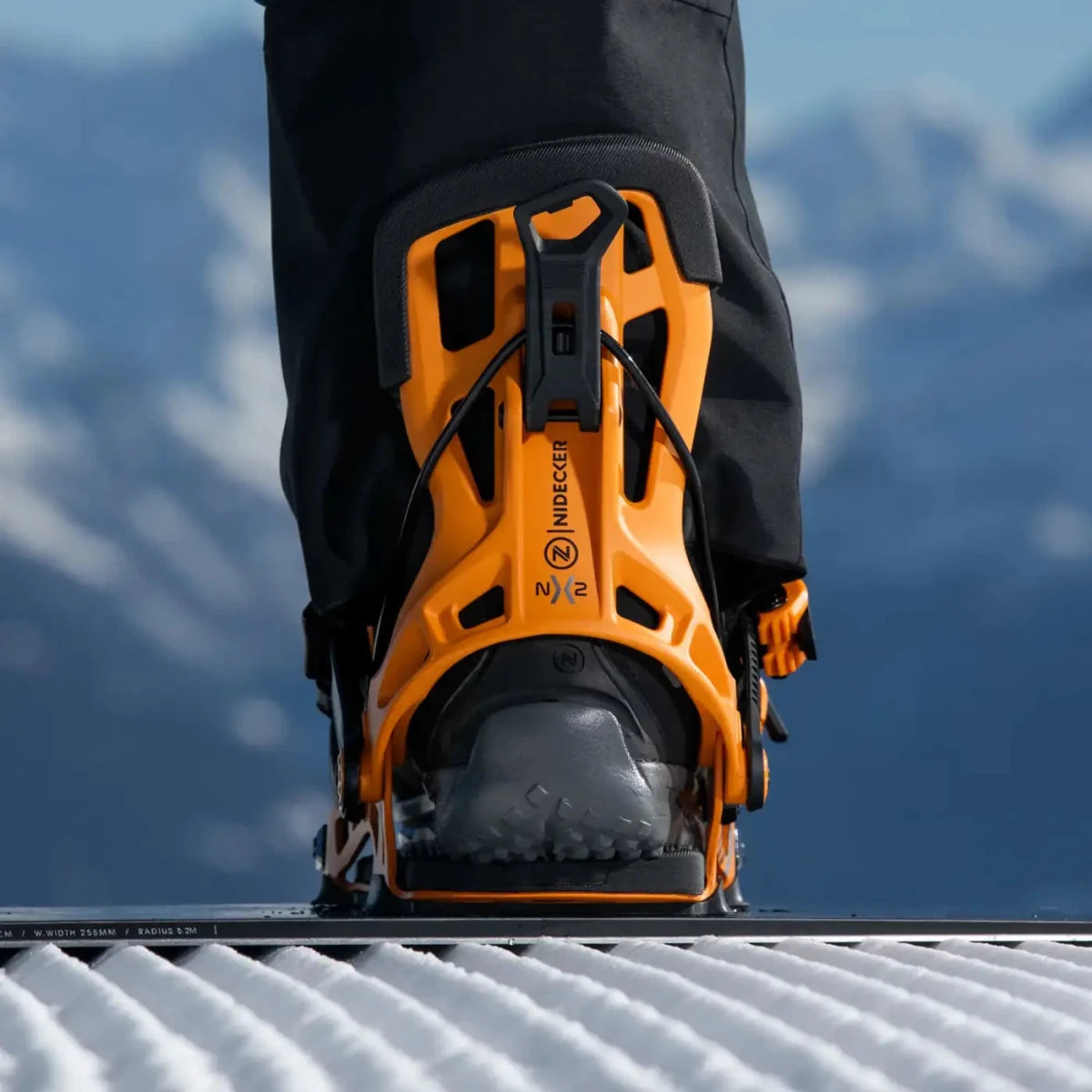 Flow NX2 Mango, binding met boot op een snowboard in de sneeuw