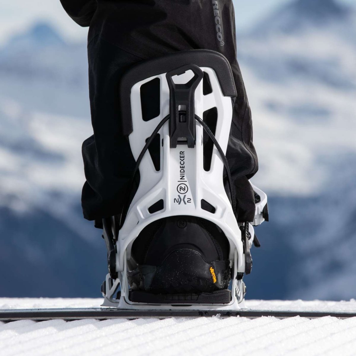 Flow NX2 White, binding met boot op een snowboard in de sneeuw