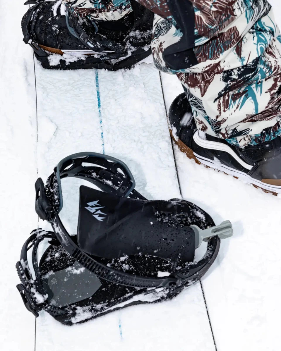 Jones Mercury FASE Stealth Black, binding en snowboardboots op een snowboard in de sneeuw