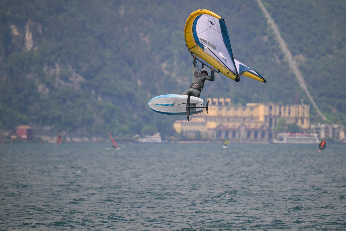 Wingfoiler springt met de Naish Mach-2 Semi Complete, frontwing en stabilizer zichtbaar onder het board