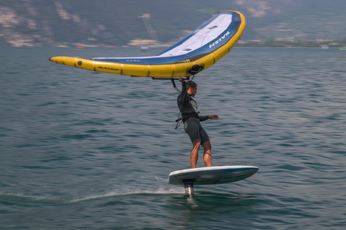 Wingfoiler op de Naish Mach-2 Semi Complete met de wing boven het hoofd