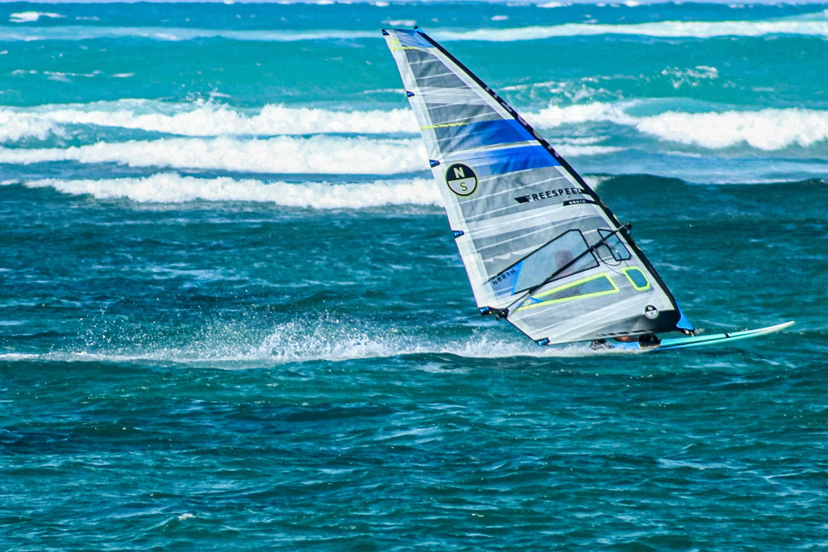Windsurfer op snelheid met het North Freespeed GEN2-zeil op turquoise zee