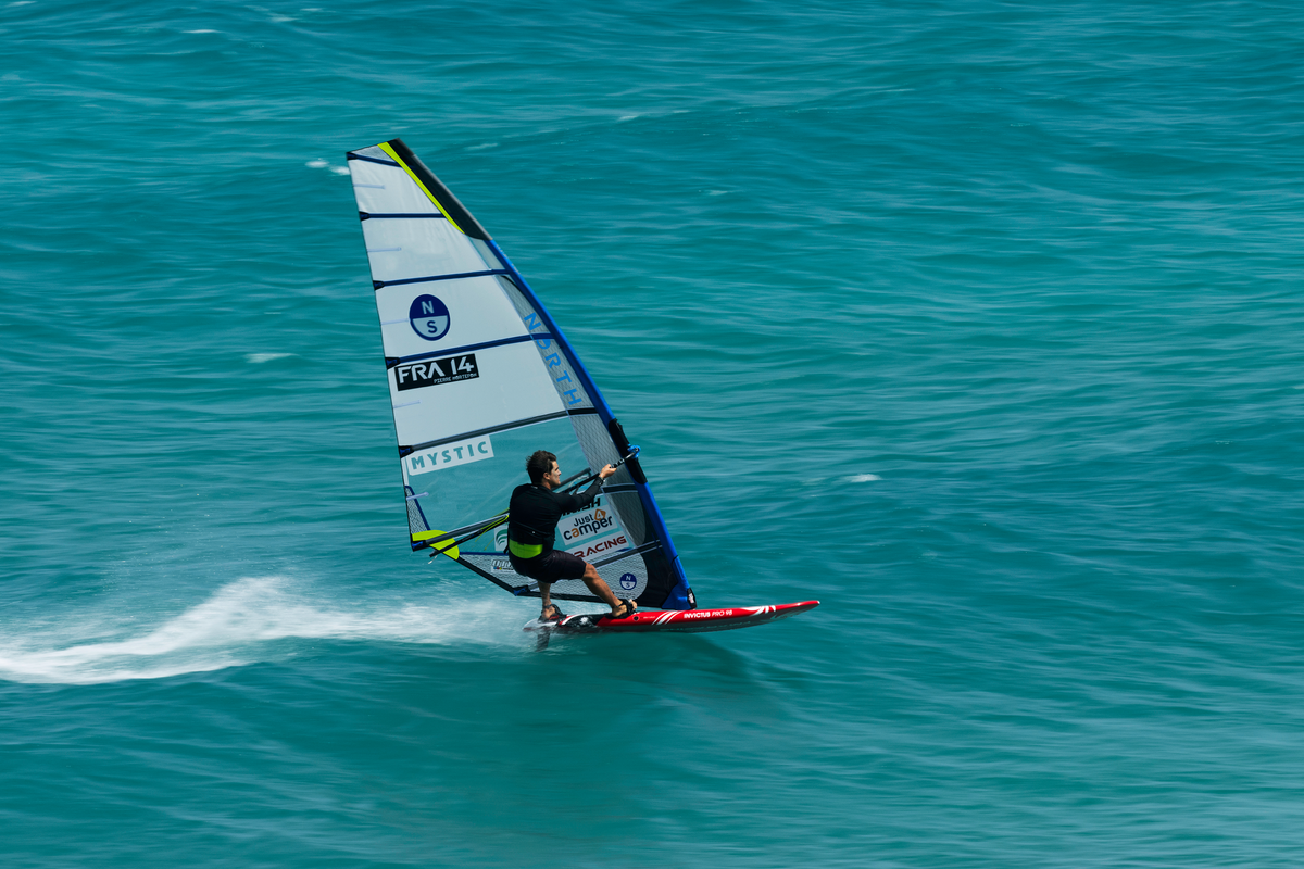 Windsurfer op volle snelheid met het North Prisma Fin racezeil op turquoise zee
