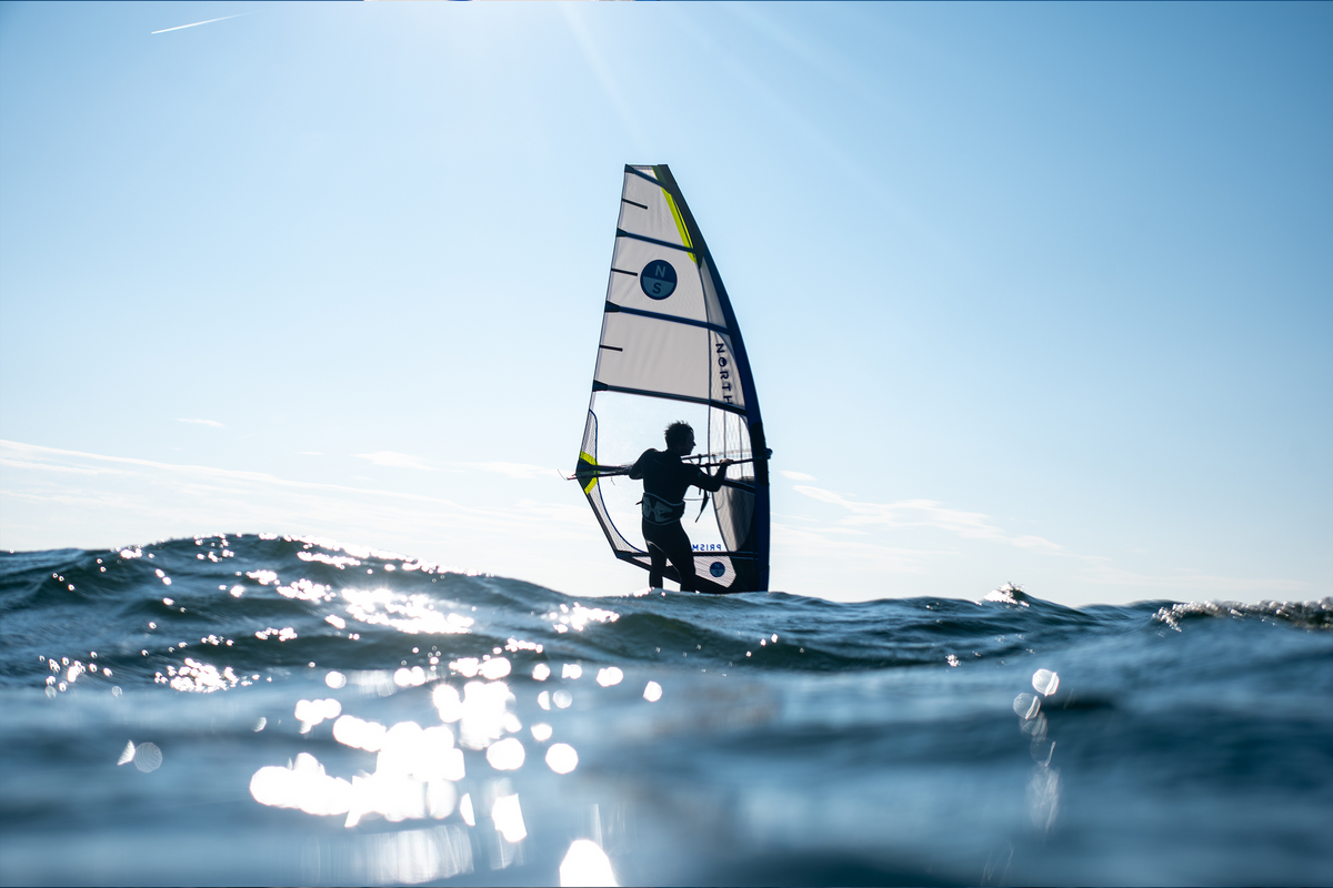 North Prisma Fin racezeil in tegenlicht op open water