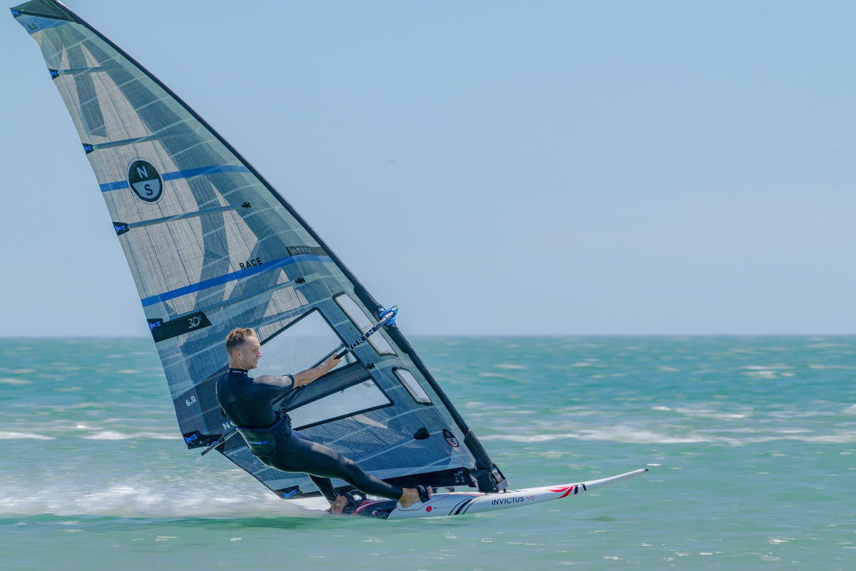 Windsurfer op snelheid met het North Slalom Race 3Di-zeil op turquoise zee