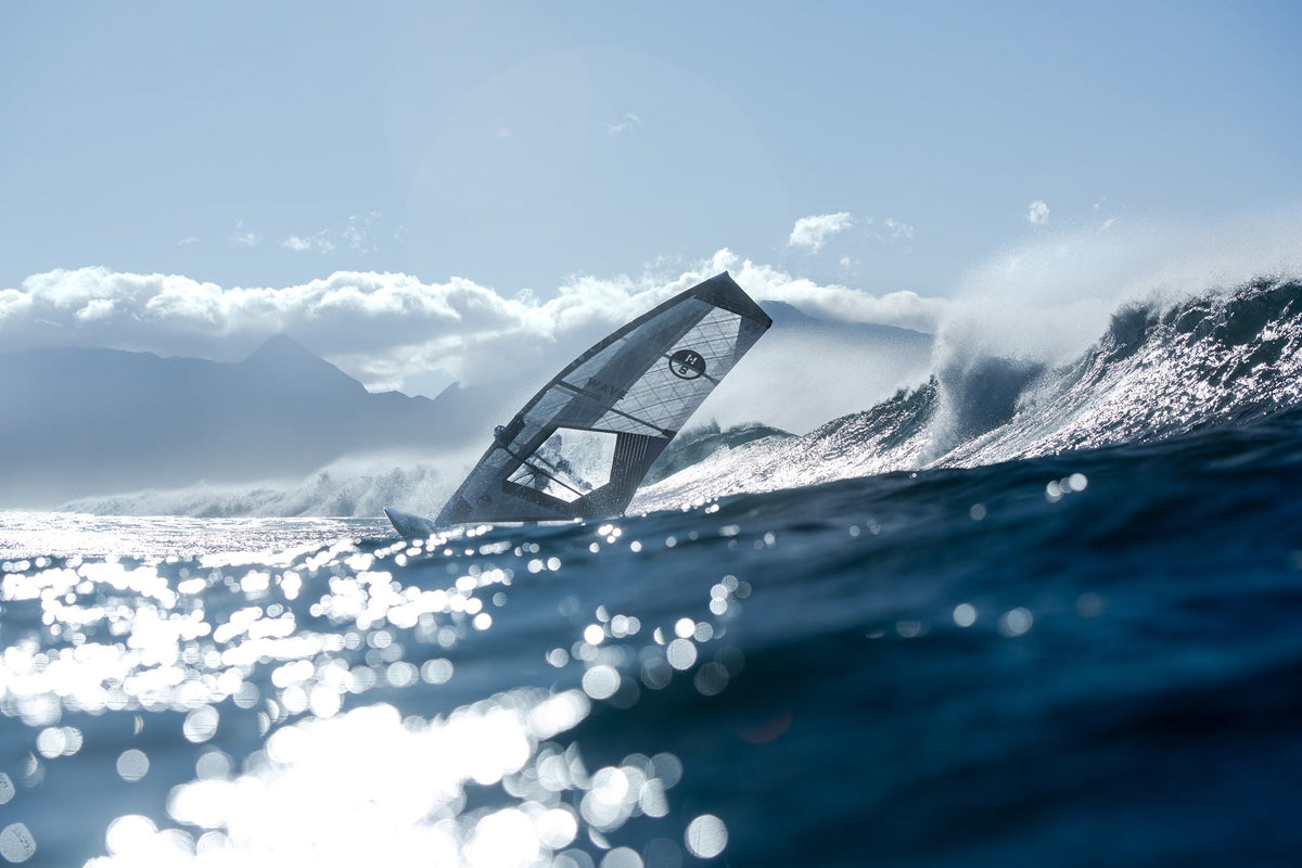 North Wave Clear-zeil in tegenlicht voor een brekende golf, gefotografeerd vanaf het water