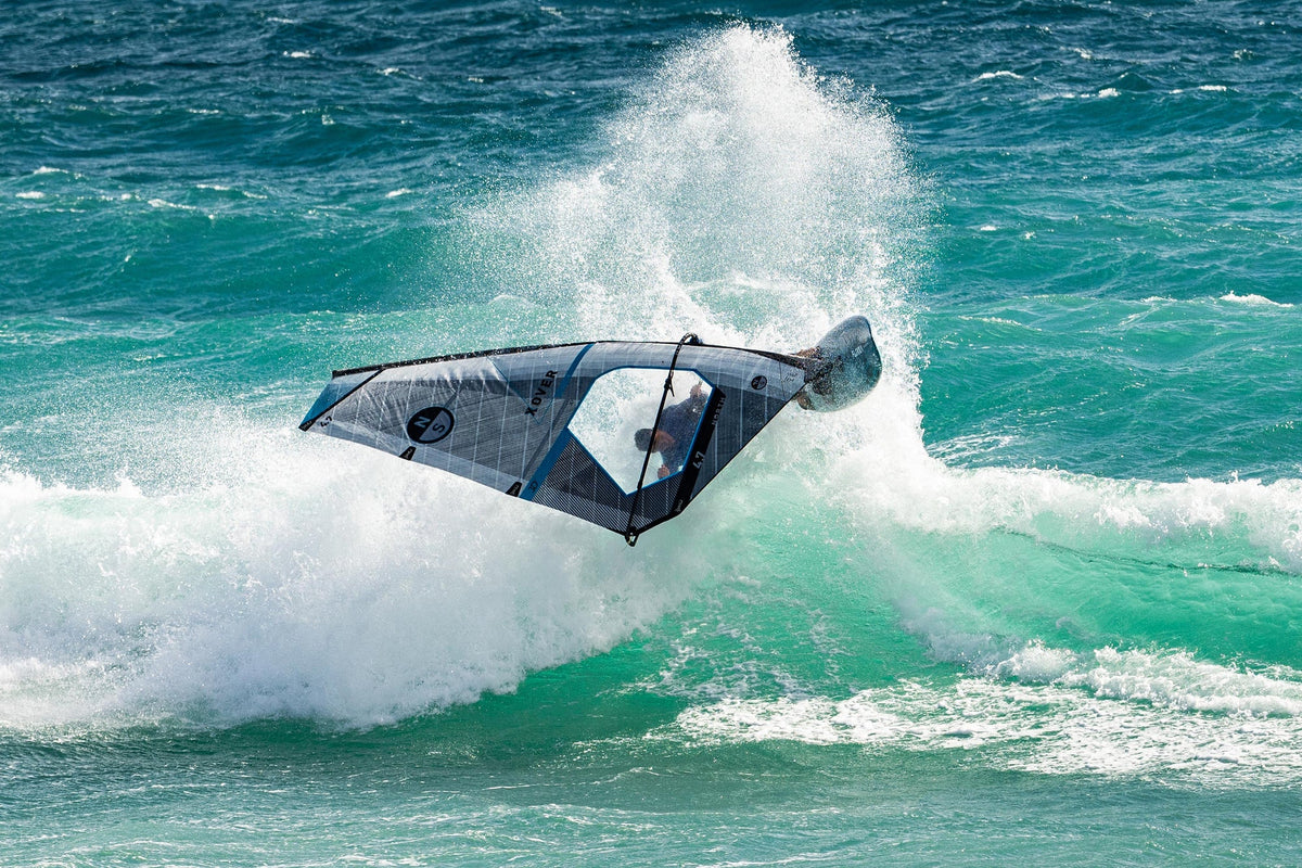 Windsurfer draait met het North X-Over GEN2-zeil op de lip van een golf, met opspattend water