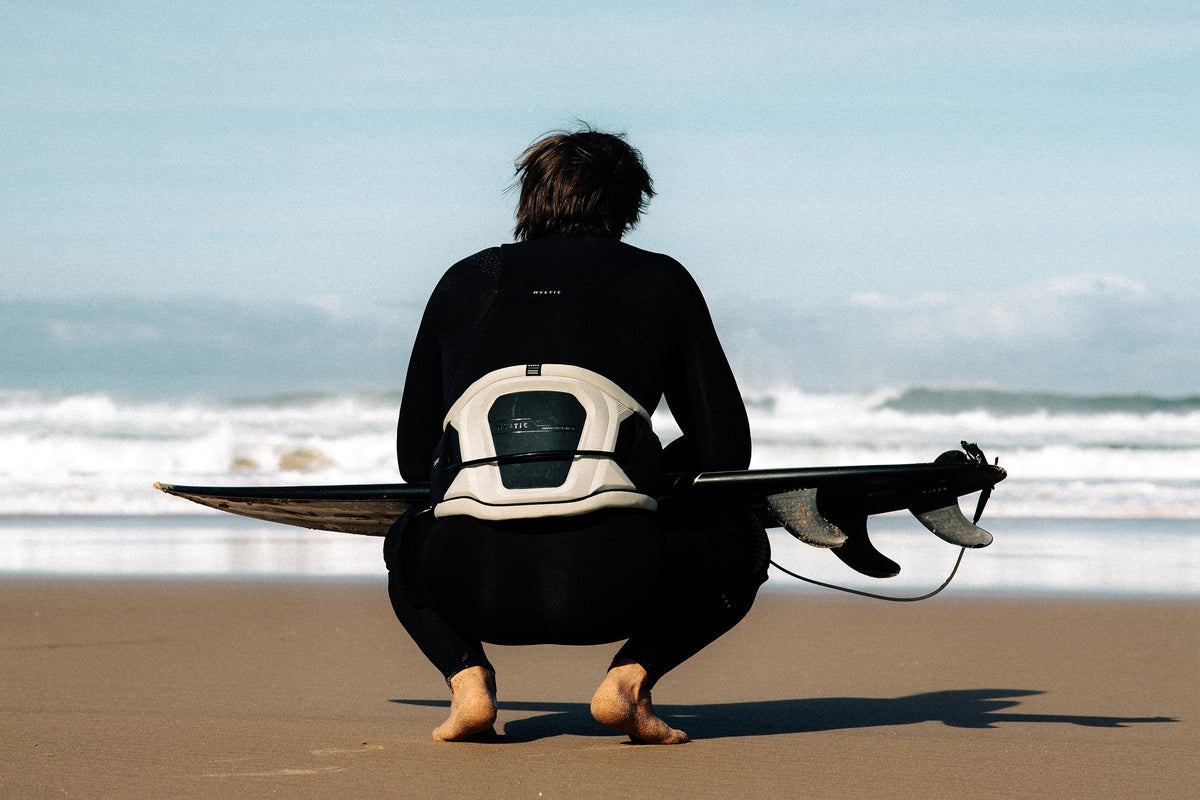 Surfer op het strand met de Mystic Warrior Waist Harness