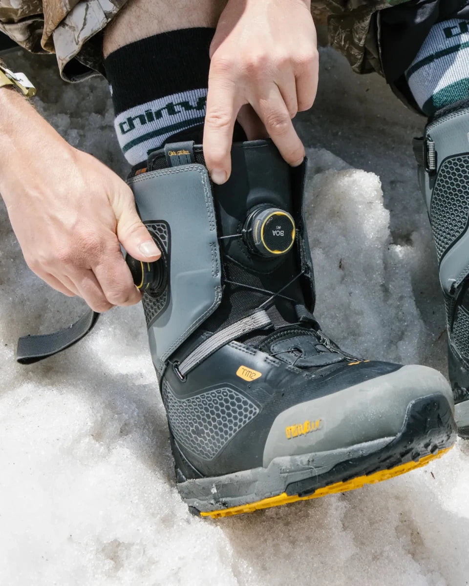ThirtyTwo TM-2 XLT DB Grenier grijs-geel, rider draait de BOA-sluiting dicht in de sneeuw
